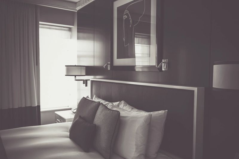 A dim, simply furnished bedroom with light coming through the blinds