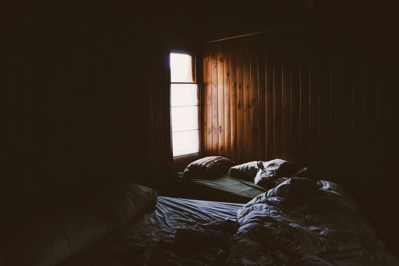 A dark bedroom lit only by the light from a small window