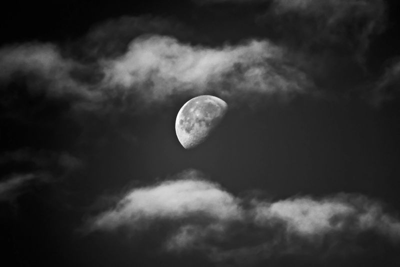 A half moon partly hidden by dark clouds at night